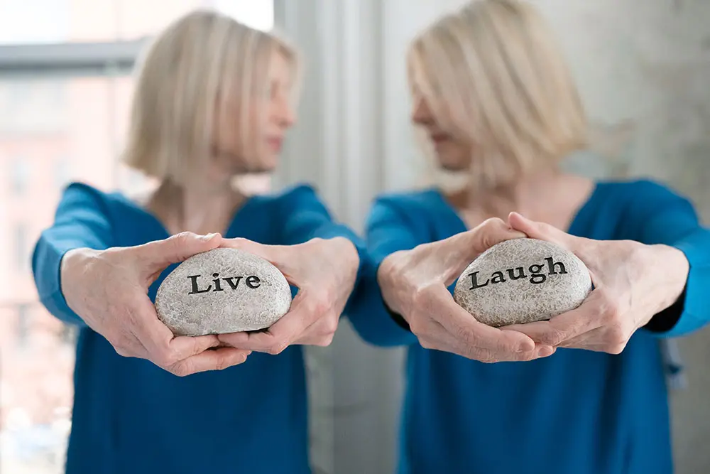 The Therapy Twins holding stones that say live and laugh